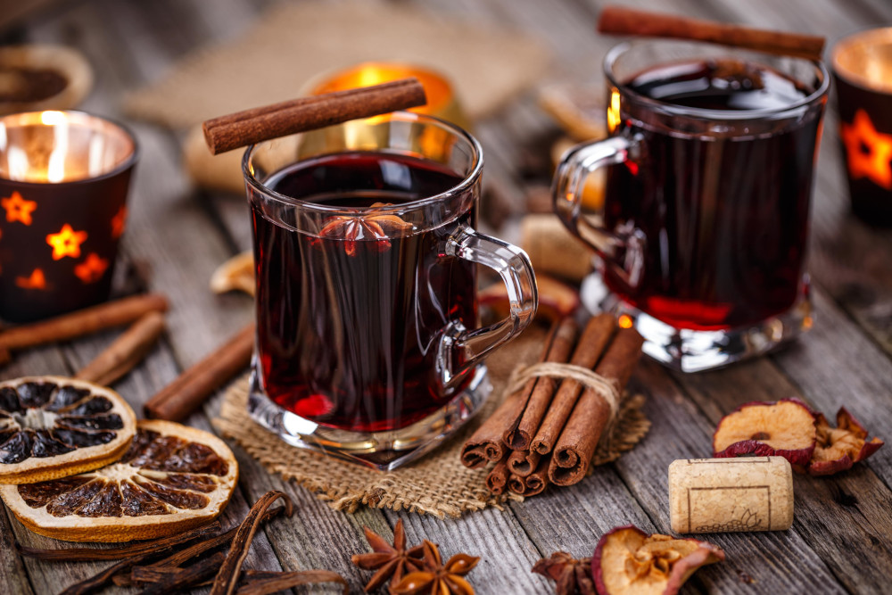 Roter Glühwein auf Tisch angerichtet mit Zimt, Orangenscheiben und Gewürzen