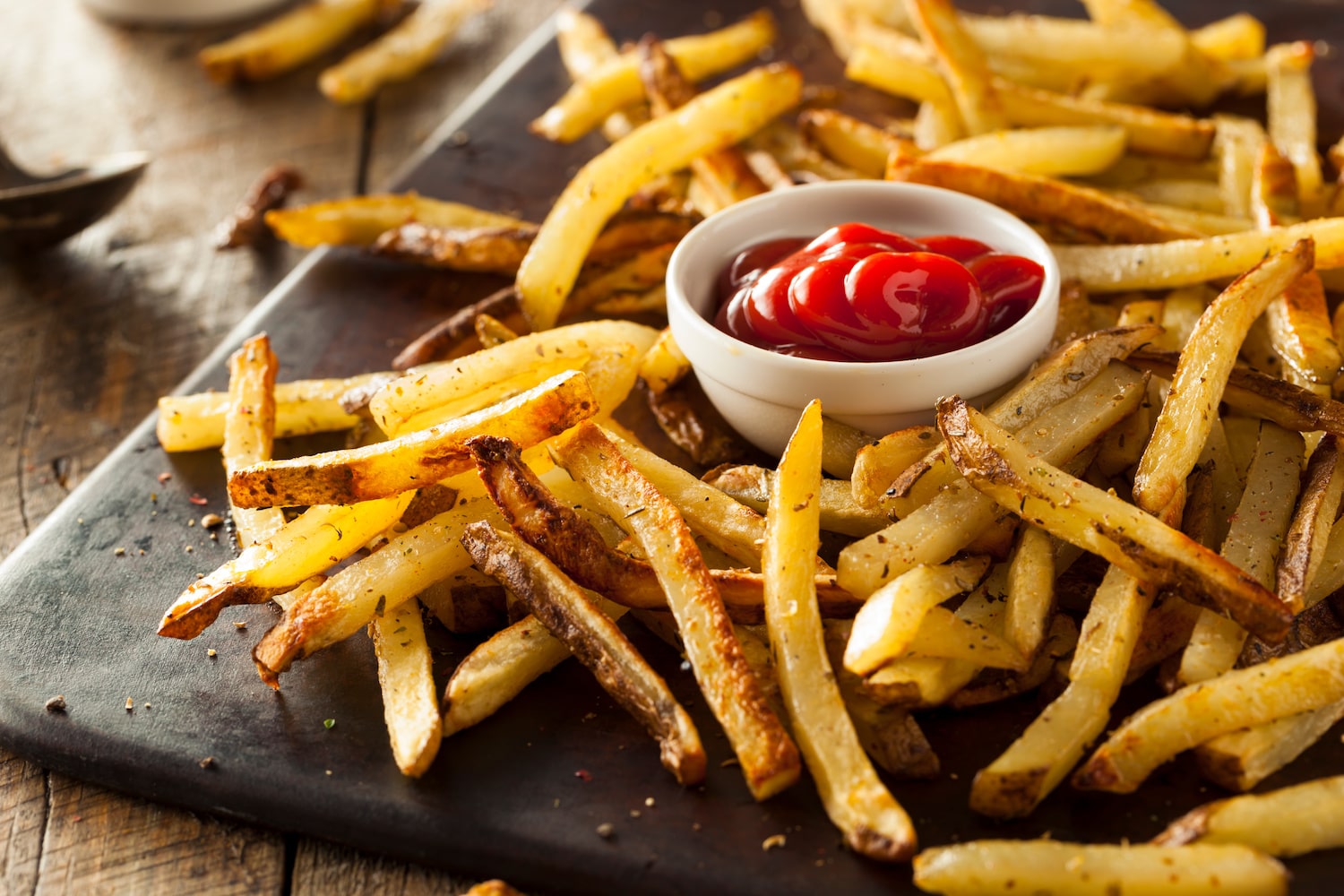 Gewürzte Pommes frites auf Schiefernplatte mit Ketchup