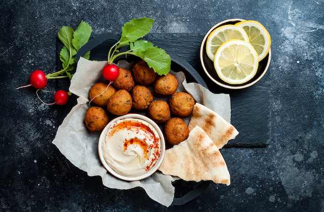 Falafel in Schüssel mit Hummus, Pitabrot und Zitronenscheiben