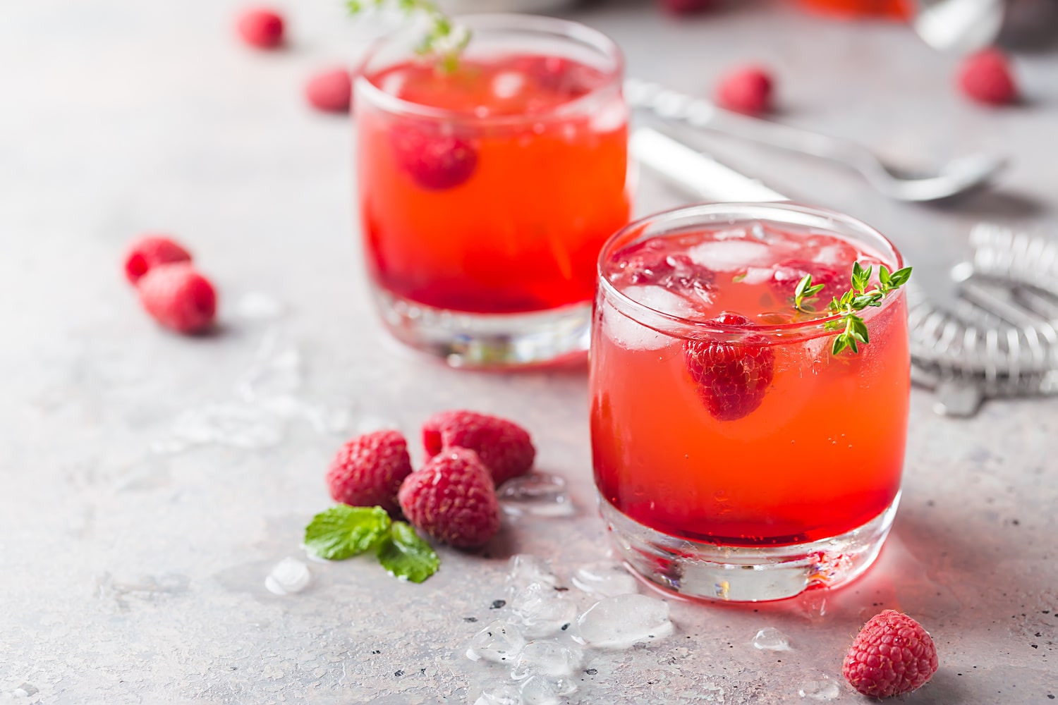 Getränk mit Himbeerlikör, Eiswürfeln und Himbeeren im Glas