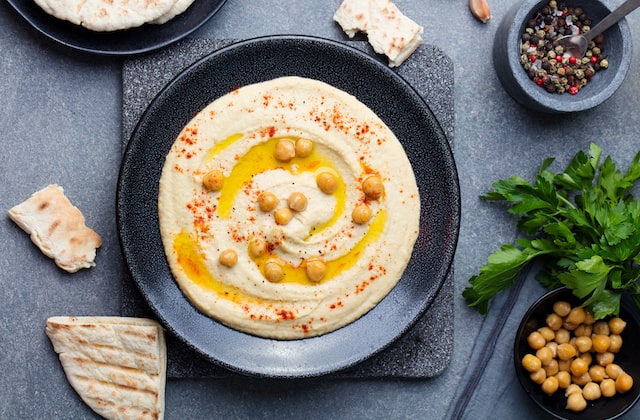 Hummus garniert mit Kichererbsen, Gewürz und Olivenöl in Schüssel