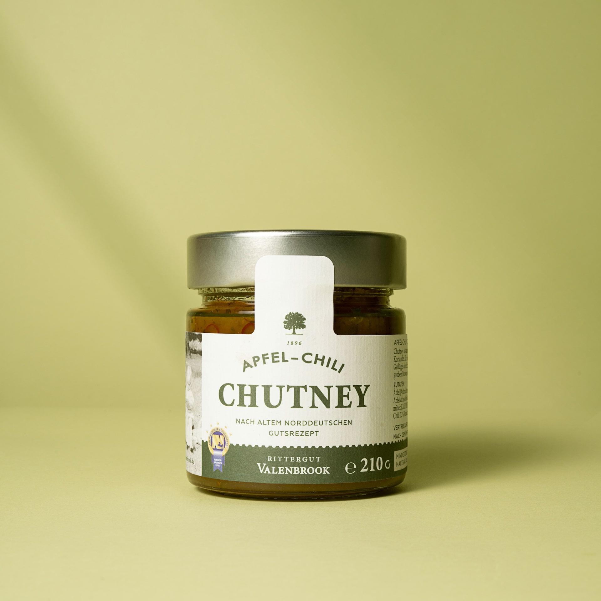 Apfel Chili Chutney im Glas vor grünem Hintergrund