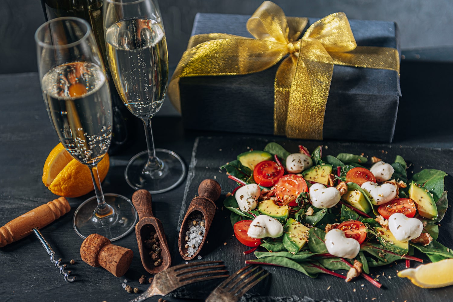 Salat mit Herz-Mozzarella, Champagner in zwei Gläsern und ein Geschenk auf Tisch